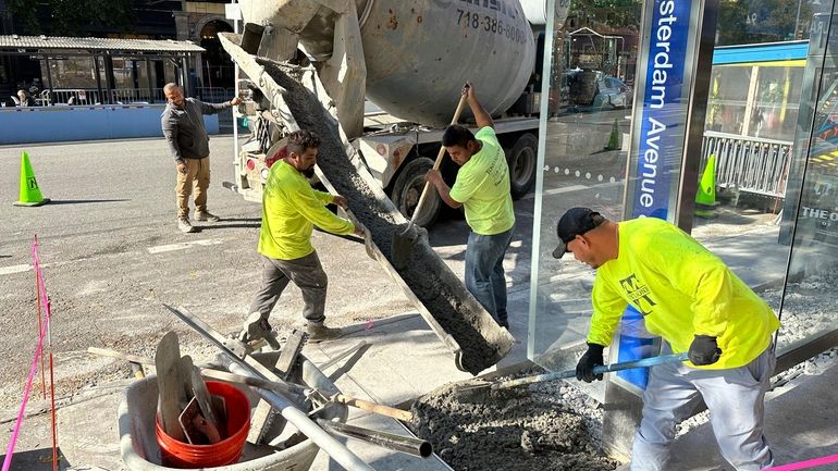 Workers pour concrete to create part of a bus stop...