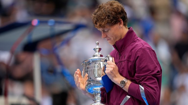 Jannik Sinner, of Italy, holds the championship trophy after defeating...