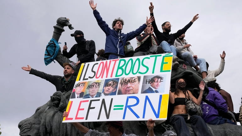 A protester holds an anti-far right banner showing the faces...