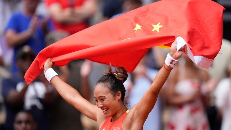 China's Zheng Qinwen holds a Chinese flag after defeating Croatia's...