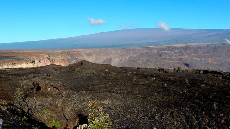 Hawaii's Mauna Loa volcano, background, towers over the summit crater...