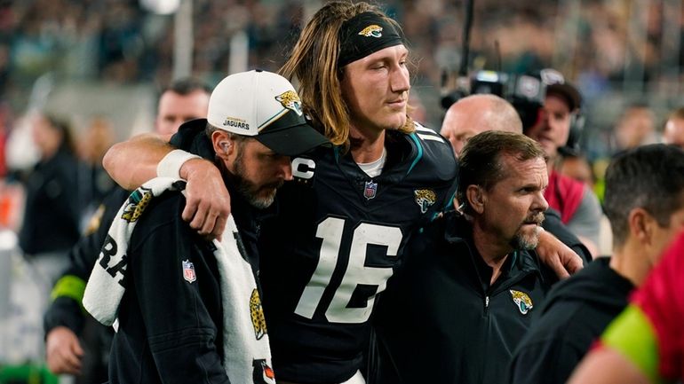 Jacksonville Jaguars quarterback Trevor Lawrence (16) is assisted off the...