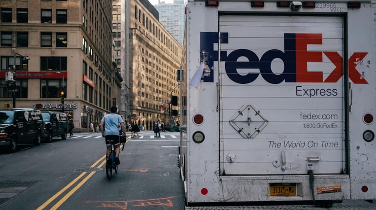 A person rides a bicycle past a FedEx Corp. delivery...
