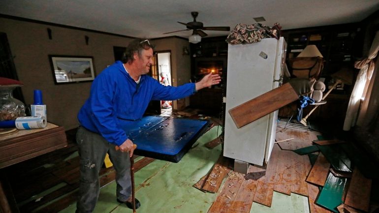 FILE-Jeff Sharp tosses flood-damaged flooring into a pile Feb. 19,...