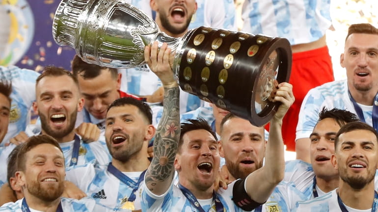Argentina's Lionel Messi holds the trophy as he celebrates with...