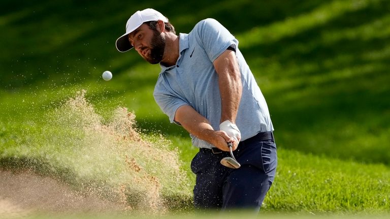 Scottie Scheffler hits from the bunker on the first hole...