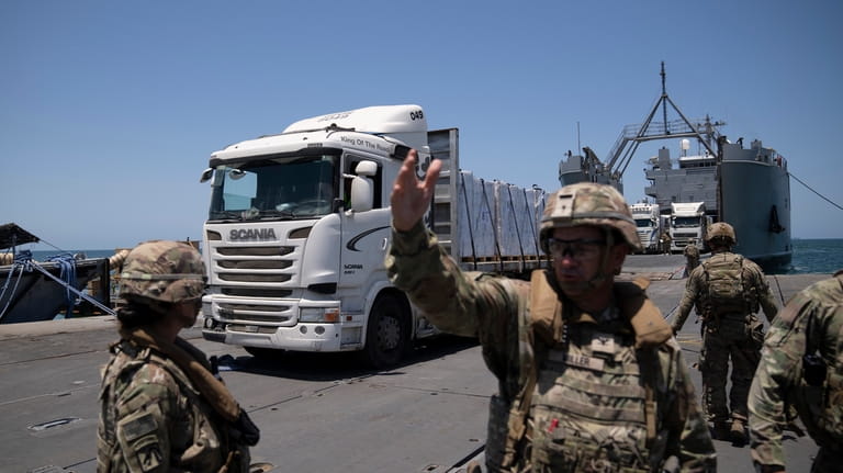 A U.S. Army soldier gestures as trucks loaded with humanitarian...