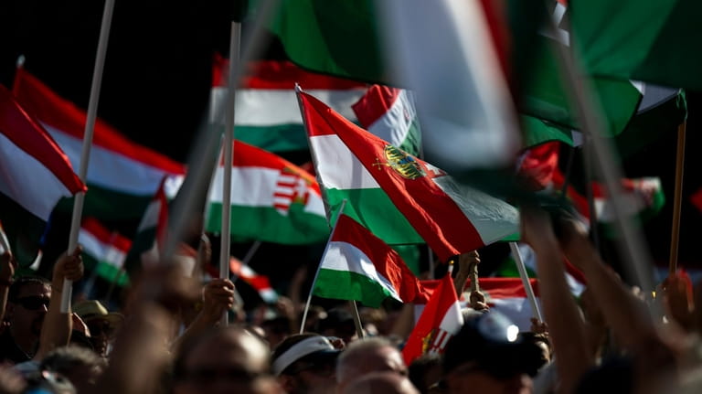 People wave the Hungarian national flag during Péter Magyar's speech...