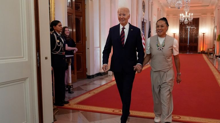 President Joe Biden walks with Dawn Staley, Coach of the...