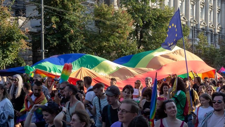 People carry a rainbow flag as they attend a pride...