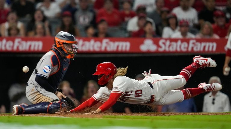 Los Angeles Angels' Jack López (10) scores as a throw...