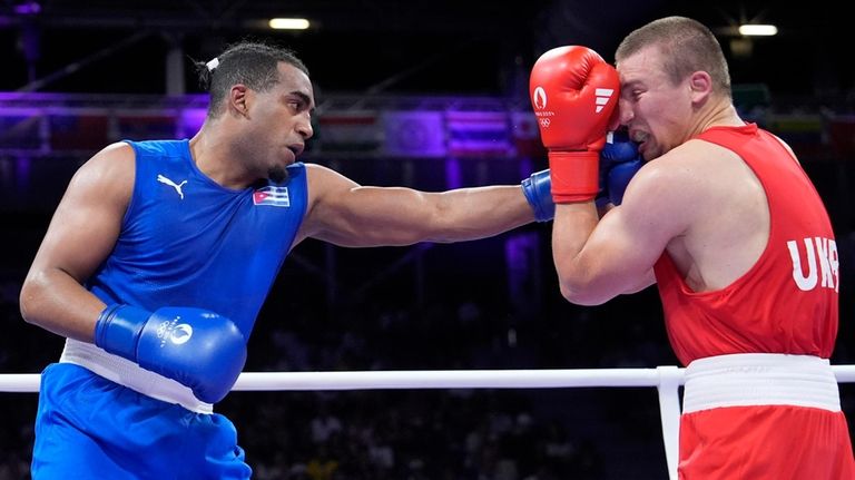 Cuba's Arlen Lopez hits Ukraine's Oleksandr Khyzhniak in their men's...