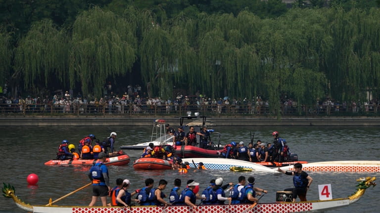 Rescuers help the dragon boat racers following a crash during...