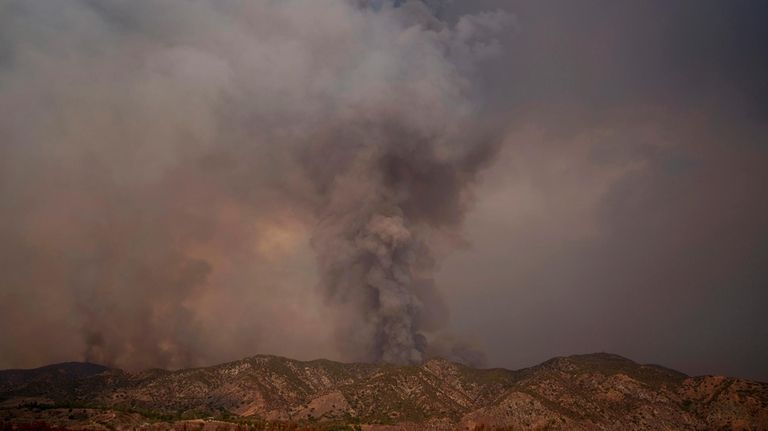 Smoke from the advancing Line Fire rises above a ridge...