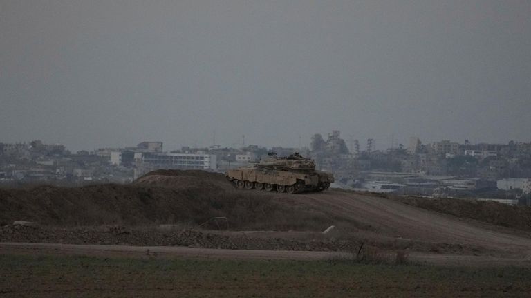 An Israeli tank overlooks the Gaza Strip, as seen from...