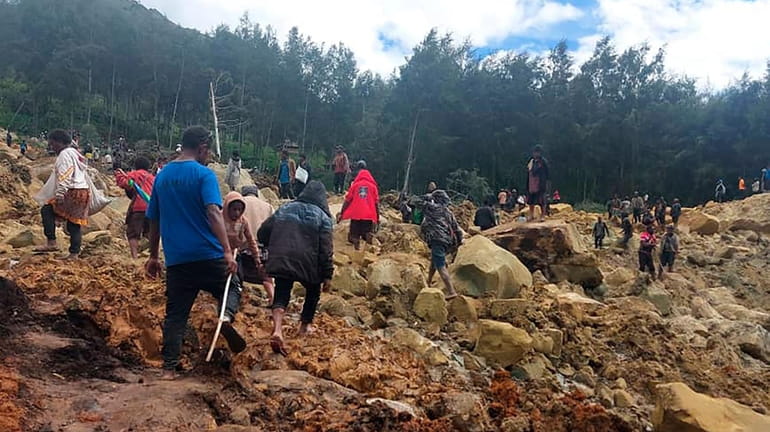 People walk over the landslide area in Yambali village, Papua...