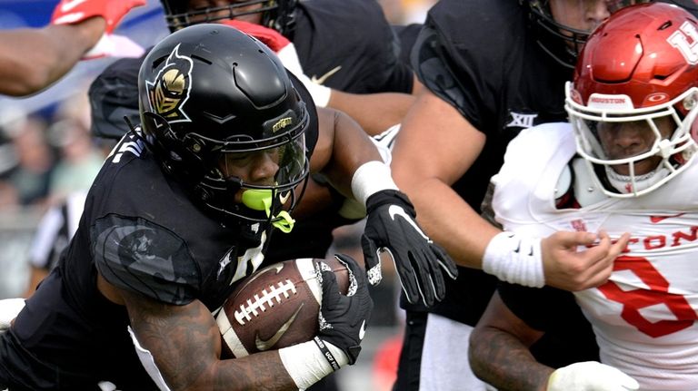 Central Florida running back RJ Harvey, left, rushes for yardage...