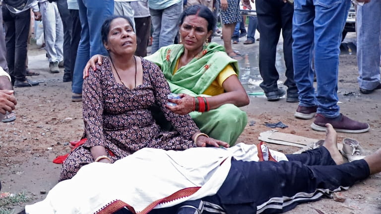 Women mourn next to the body of a relative outside...