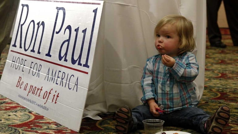Eisley Collins, 2, snacks next to a Ron Paul sign...