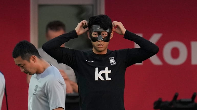 South Korea's Son Heung-min adjusts his mask during a training...