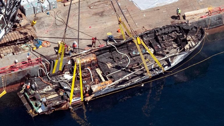 The burned hull of the dive boat Conception is brought...