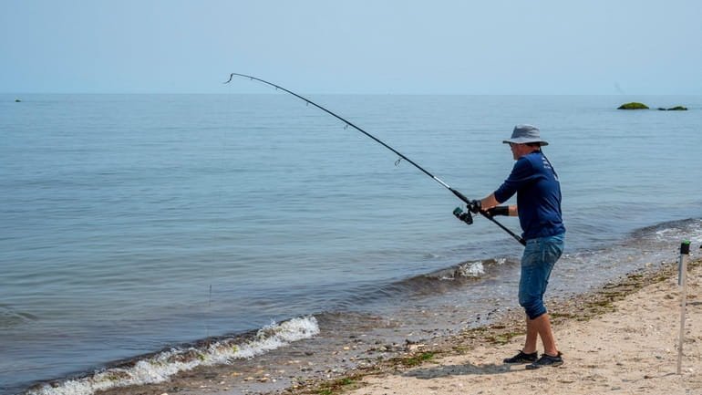 A fisherman casts at Woodhull Landing Beach, on the border...