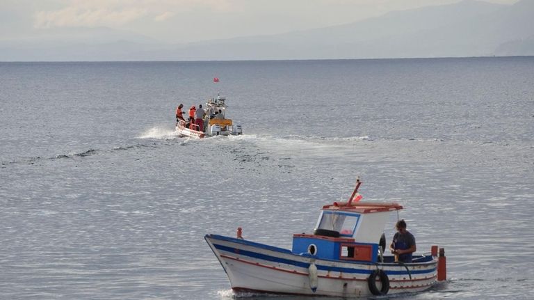 A boat, top, carrying a dive team passes a fishing...