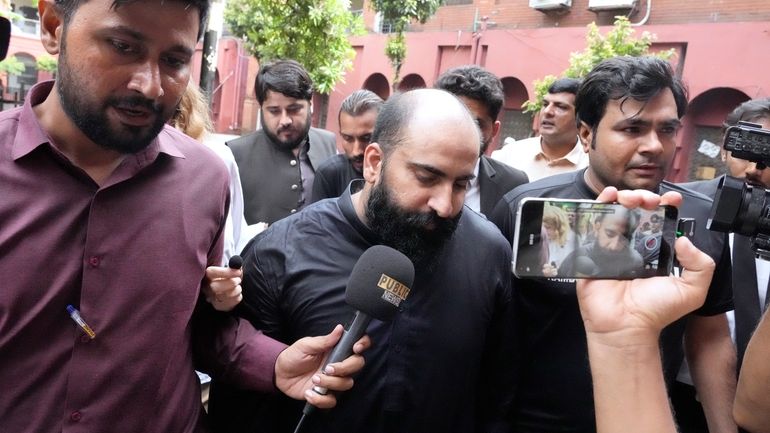 Members of media chase Farhan Asif, center, a freelance web...