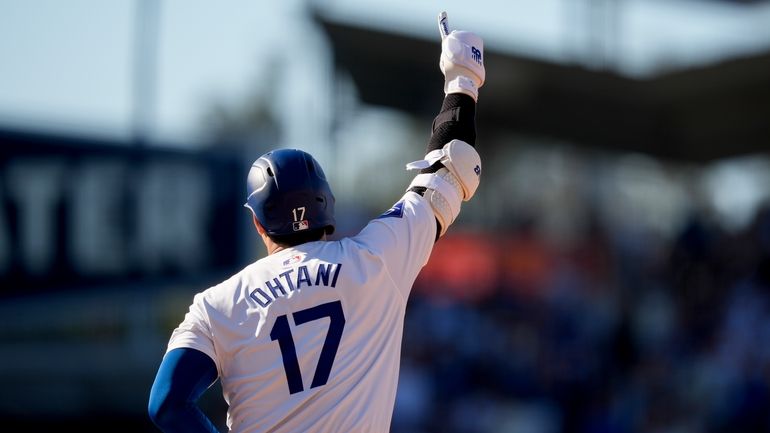 Los Angeles Dodgers designated hitter Shohei Ohtani celebrates while running...