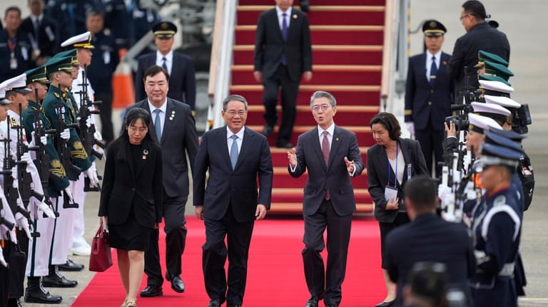 Chinese Premier Li Qiang, center left, is welcomed by Kim...