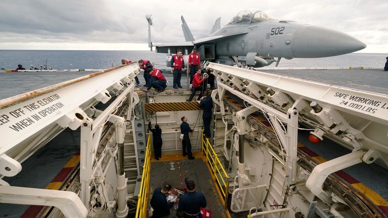 Weapons personnel work on a weapons elevator on the flight...