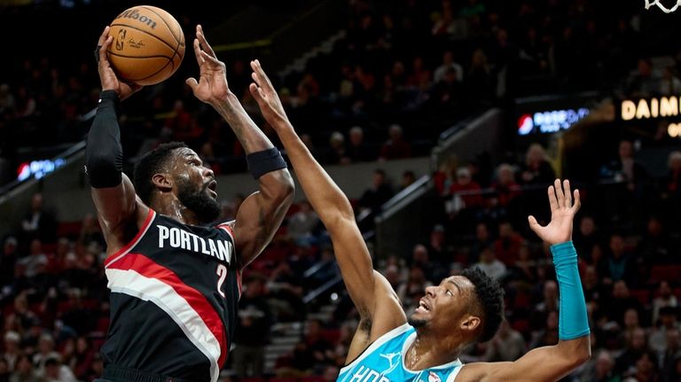 Portland Trail Blazers center Deandre Ayton, left, shoots over Charlotte...