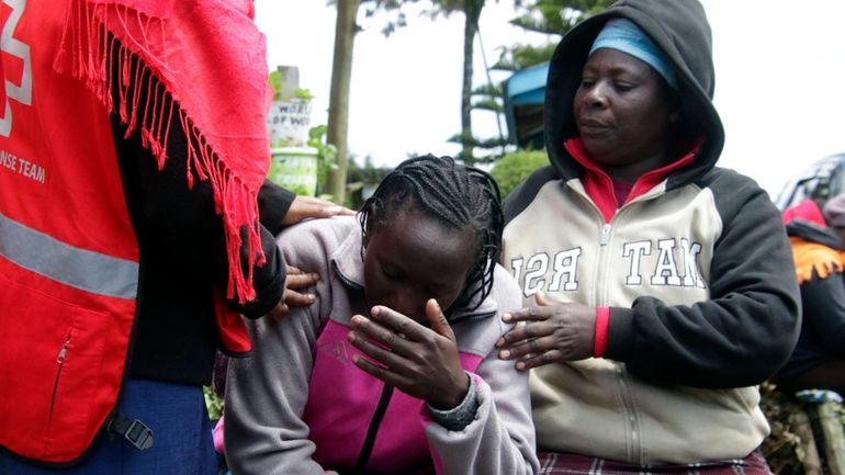 Kenya Red Cross personnel and relatives try to comfort a...