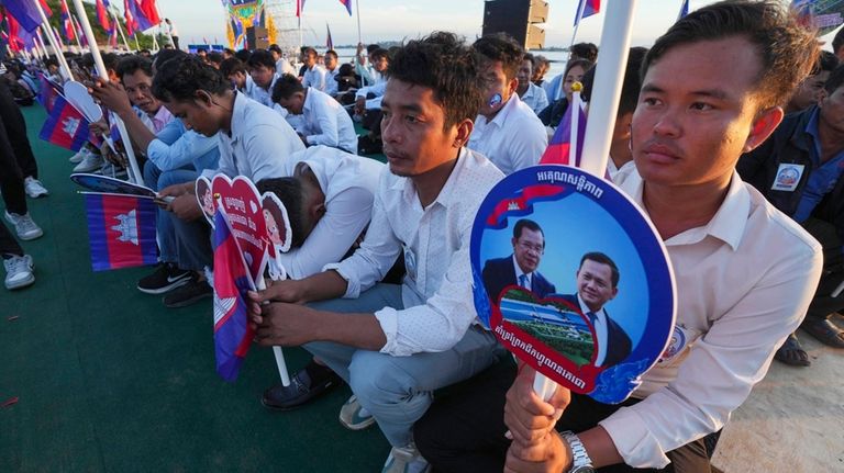 Cambodian civil servants hold photographs of their Prime Minister Hun...