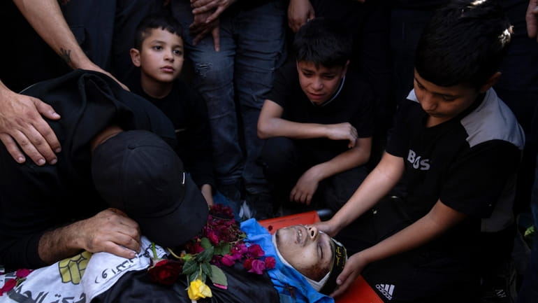 Relatives mourn over the body of a Palestinian man, draped...