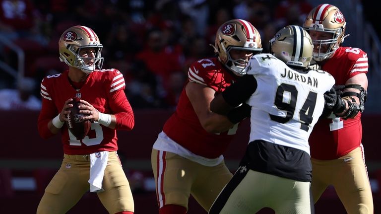 San Francisco 49ers quarterback Brock Purdy, left, drops back to...