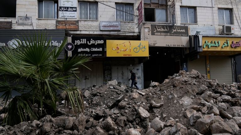 A Palestinian walks on a damaged street during a military...