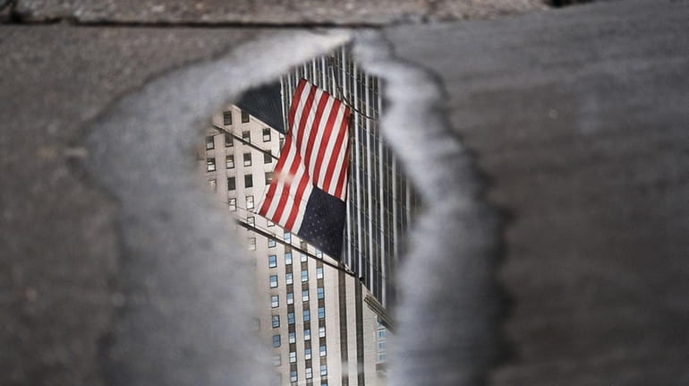 An American flag is reflected in a puddle outside of...