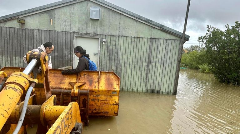 Residents are rescued from flood waters in a front loader,...