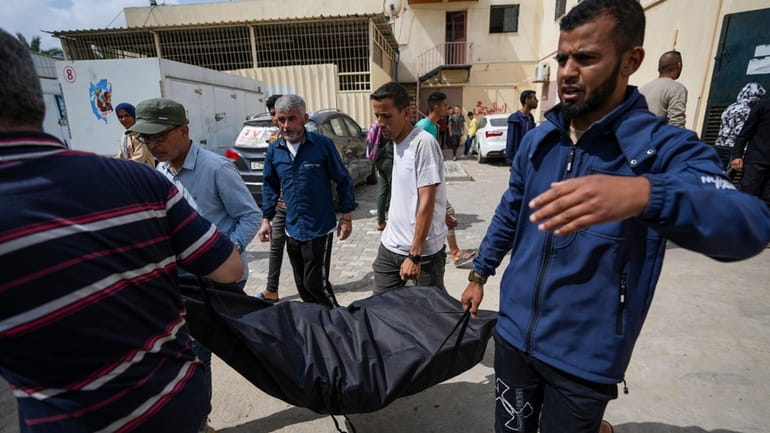 People carry the bodies of Palestinians who were killed in...