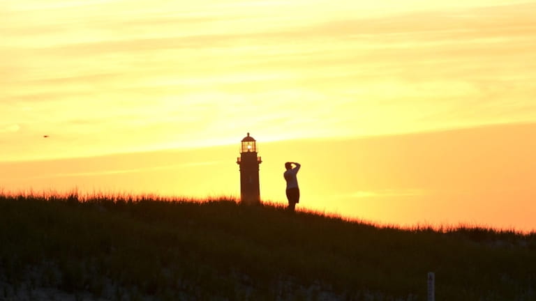 A man photographs the sunrise at Robert Moses State Park...