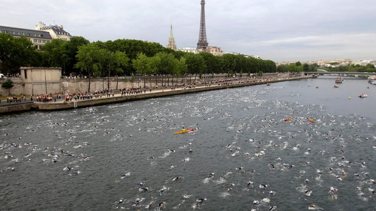 Competitors swim in the Seine River during the Paris Triathlon...