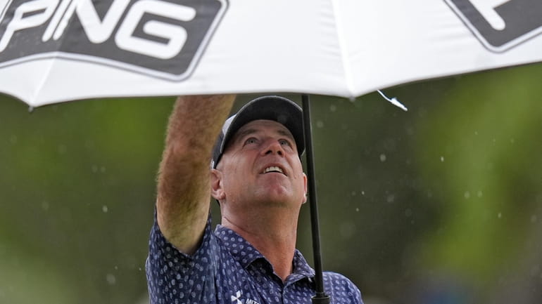 Stewart Cink puts his his umbrella as the rain begins...