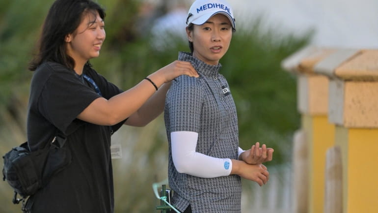 Narin An, right, gets a shoulder rub before teeing off...