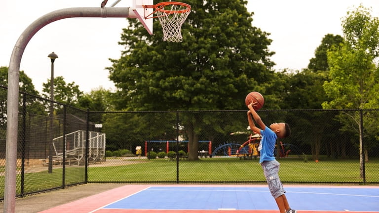 Ethan Calliste, 9, of Wyandanch, shoots hoops inside the basketball...