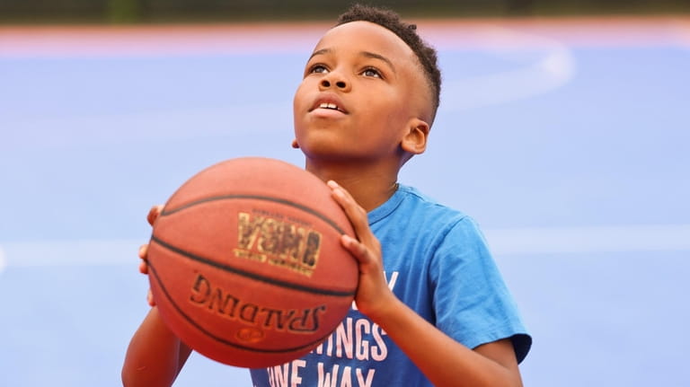 Ethan Calliste, 9, of Wyandanch, shoots hoops inside the basketball...