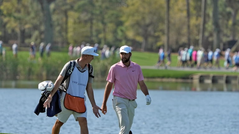 Scottie Scheffler, right, walks with his caddy along the 18th...